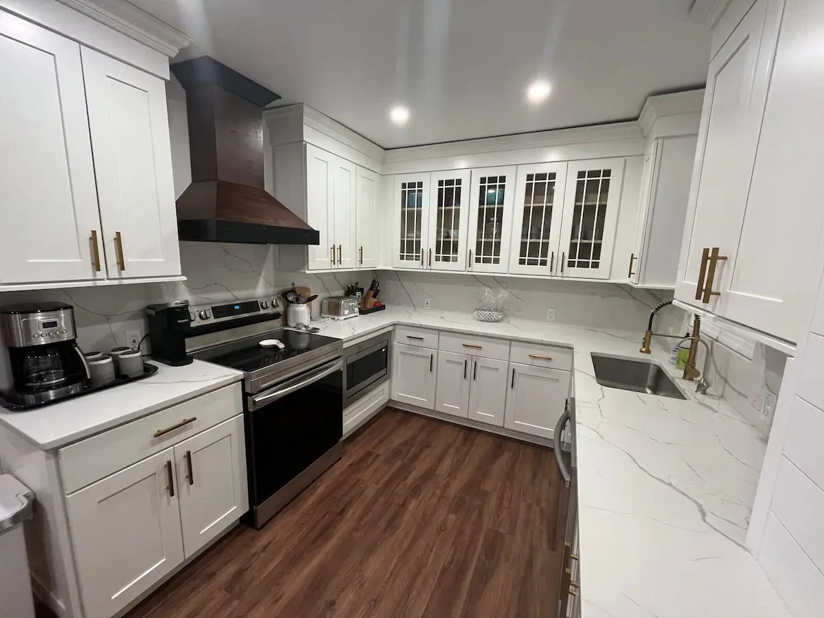 A kitchen with white cabinets and wood floors.