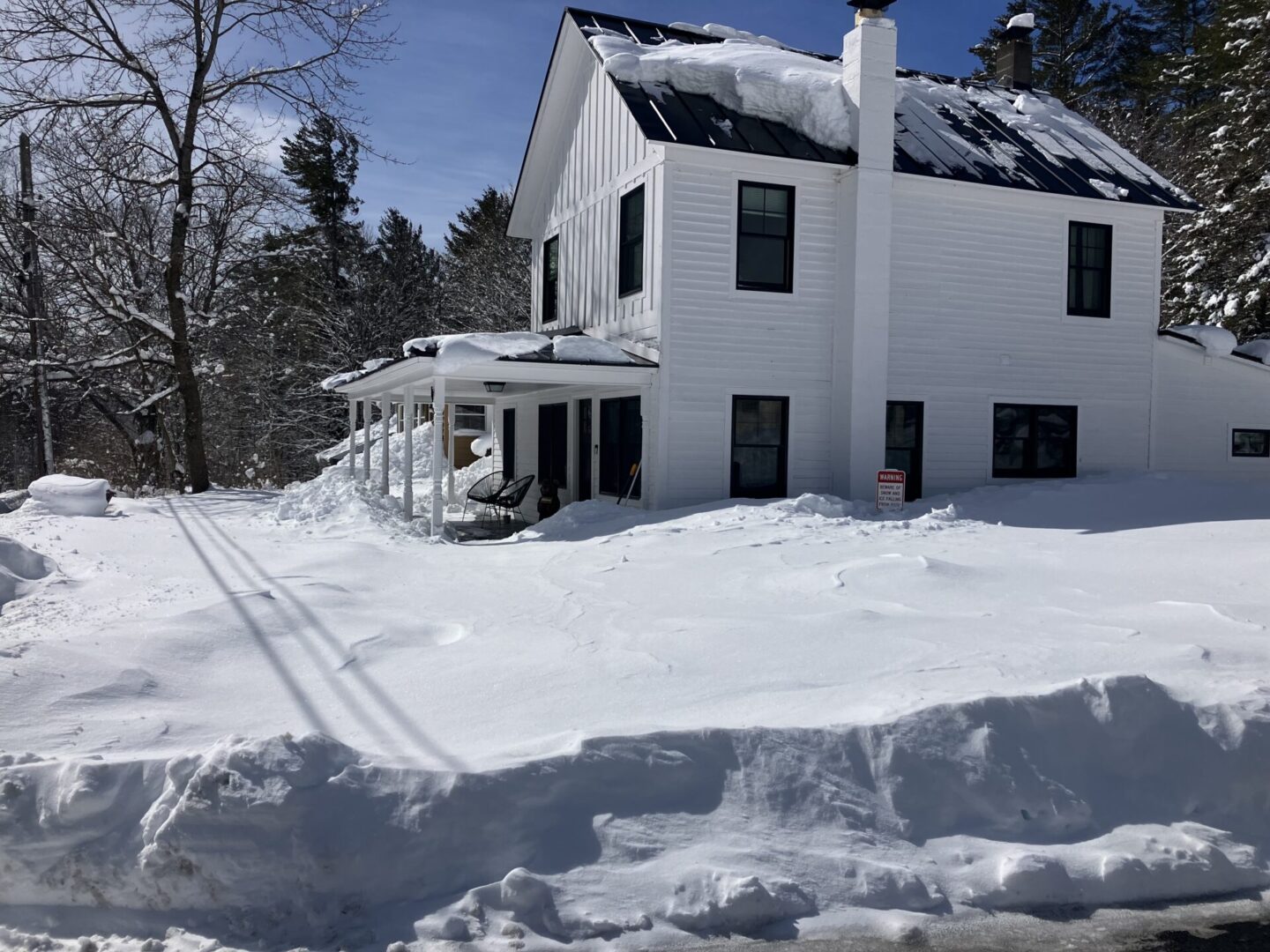 A house with snow piled up on the ground.