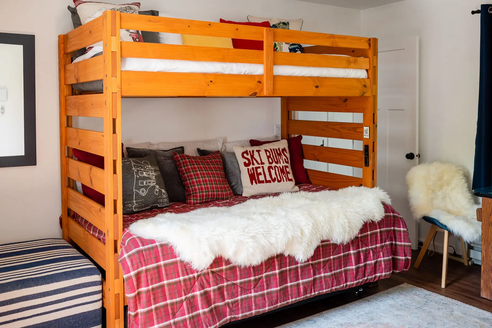 A bunk bed with red plaid sheets and pillows.